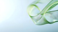 Elegant flowing green silk fabric creates smooth waves and curves against light background, showcasing delicate textile movement and graceful design elements.