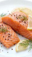 Fresh salmon fillets with lemon slices and dill herbs seasoned with black pepper on white background for culinary cooking and healthy seafood recipes.