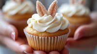 Vanilla cupcake with cream cheese frosting swirls topped with sugar-coated butterfly wings decoration, soft bokeh background creates dreamy dessert mood.