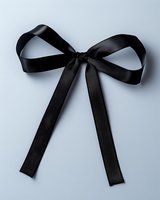 Elegant black satin bow ribbon isolated on light gray background. Classic decorative element for fashion, gifts and holiday designs.