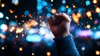 Raised fist silhouette against blurred bokeh lights and sparkler fireworks creating magical atmosphere. Concept of celebration, victory, protest and freedom.