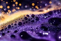Abstract purple liquid surface with golden bokeh lights and water droplets creating dreamy atmospheric background for luxury design projects.