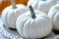 White decorative pumpkins arranged on vintage silver tray create elegant autumn display with soft selective focus and natural lighting for seasonal decor.