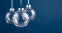 Clear glass Christmas ornament baubles hanging against blue background for holiday decoration and festive seasonal design projects.