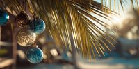 Festive ornaments hanging from palm fronds with sunlight creating warm holiday atmosphere in tropical setting.