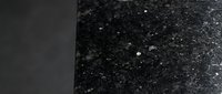 Smooth dark surface transitioning to textured black granular material with sparkling particles, suitable for backgrounds, design elements, and abstract compositions.