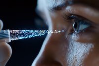 Macro shot of eye drops application with sparkly liquid droplets creating magical effect against dark background, showing skincare and eye care concept.