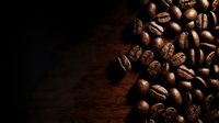 Roasted coffee beans scattered on dark wooden surface with copy space for beverage, café, or food industry design projects.