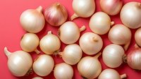 Fresh white and yellow onions scattered on vibrant pink background for cooking, kitchen design, healthy eating concepts and culinary presentations.