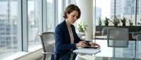 Professional businesswoman using smartphone in modern office with city view, corporate communication and technology in workplace.