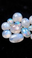 Collection of natural opal gemstones displaying iridescent rainbow colors and fire flashes on black background for jewelry making and mineral collecting.