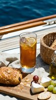 Iced cola beverage with fresh pastry, cheese, grapes and crackers on wooden deck of luxury yacht with ocean water backdrop, perfect for nautical dining and leisure lifestyle content.