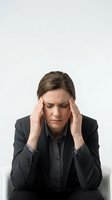 Stressed businesswoman in dark suit holding temples with headache pain isolated on white background for workplace wellness and mental health concepts.