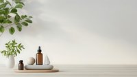 Minimalist spa composition with amber glass bottles, ceramic bowls and green plants on wooden surface against neutral wall. Natural cosmetics concept.