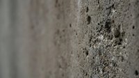 Rough textured concrete wall surface with natural pores and weathered finish for industrial architecture and construction backgrounds.