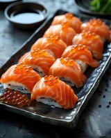 Fresh salmon nigiri sushi rolls topped with orange roe served on black ceramic plate, close up view with soy sauce. Traditional Japanese cuisine preparation.