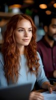 Young redhead woman working on laptop in modern cafe with warm lighting and blurred background for business and lifestyle concepts.
