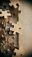 Wooden jigsaw puzzle pieces scattered on textured surface with warm lighting creating shadows and depth for problem solving and teamwork concepts.