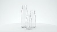 Three empty glass bottles of different sizes arranged on white background, transparent containers for beverages, milk, water or juice packaging design.