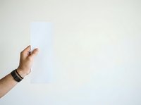 Male hand holding blank white paper sheet against neutral background, suitable for advertising, mockup designs, and promotional campaigns.