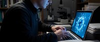 Professional businessman working late on laptop with digital network visualization in modern office environment for technology and business concepts.