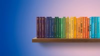 Colorful books arranged by rainbow spectrum on wooden shelf against gradient blue to pink background for education and learning concepts.