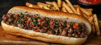 Sloppy joe sandwich with seasoned ground beef, diced tomatoes and fresh herbs on toasted bun, served with golden french fries on wooden board.