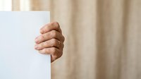 Mature man's hand gripping white edge of wall or board against neutral beige background, suitable for advertising, marketing, and promotional campaigns.
