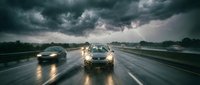 Cars driving on wet highway during dramatic thunderstorm with dark clouds and lightning. Dangerous weather conditions for road travel and transportation.
