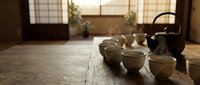 Traditional Japanese tea ceremony setup with ceramic teapot and cups on wooden table in authentic tatami room with natural lighting for cultural meditation.