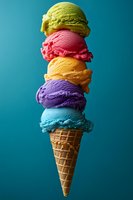 Colorful ice cream scoops stacked in waffle cone against turquoise background. Five different flavors creating vibrant summer dessert composition.