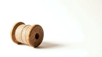 Wooden spool with natural twine thread isolated on white background for crafting and sewing projects.