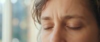 Young woman with closed eyes in peaceful meditation or relaxation moment, soft natural lighting creating serene atmosphere for wellness and mindfulness content.