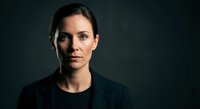 Professional portrait of confident Caucasian businesswoman in black attire against dark background for corporate branding and marketing materials.