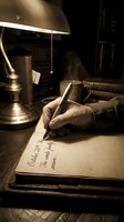 Writer's hand holding pen over open journal at desk with brass lamp and coffee cup in warm lamplight, suitable for literature, creativity, writing, and storytelling projects.