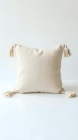 Neutral linen throw pillow with corner tassels on white background, boho home decor accent for living room or bedroom styling.