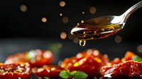 Dripping honey from spoon over sun-dried tomatoes garnished with fresh basil leaves against dark background with bokeh lights, food photography styling.