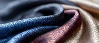 Luxurious leather textures in blue, burgundy and beige with embossed decorative pattern, close-up macro shot showing material grain and surface details.
