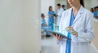 Female doctor in white coat using digital tablet with holographic medical interface displaying healthcare data and analytics in modern hospital setting.