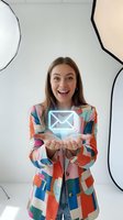Young woman with long brown hair and fair complexion, wearing a colorful geometric patterned blazer, holding a glowing neon envelope icon in her hands against a white background with abstract line art. Concept for email, messaging, communication, newsletter signup, contact us, digital marketing.