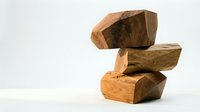 Stacked wooden blocks in warm tones arranged in abstract balance, showcasing natural grain patterns and textures for design and construction concepts.