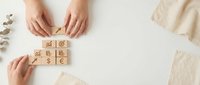 Business woman arranging wooden blocks with financial symbols on white desk for investment planning and wealth management strategy presentation.