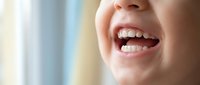 Close-up of young woman's genuine smile showing white teeth and natural expression in soft natural lighting for dental health and wellness concepts.