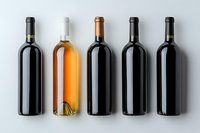 Five wine bottles arranged in row on light background - red, rose and white wines showing variety of colors and styles in minimalist composition.