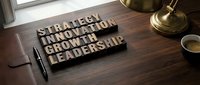 Strategy, innovation, growth, and leadership wooden letters arranged on a desk with notebook, pen, and lamp for business concepts.