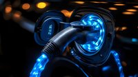 Electric vehicle charging plug glowing with bright blue light against dark background, modern EV technology concept for sustainable transportation.