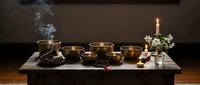 Tibetan singing bowls meditation setup with burning incense and candle creating peaceful spiritual atmosphere for sound healing therapy and mindfulness practice.