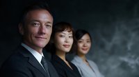 Diverse business team of professionals in formal attire against dark background, showcasing leadership and collaboration in corporate environment.