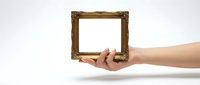 Hand holding ornate wooden picture frame with empty space for custom content, isolated on white background for design projects and creative presentations.