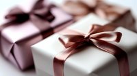 Elegant gift boxes wrapped in white and pink paper with satin bronze and burgundy ribbons tied in bows, perfect for special occasions.